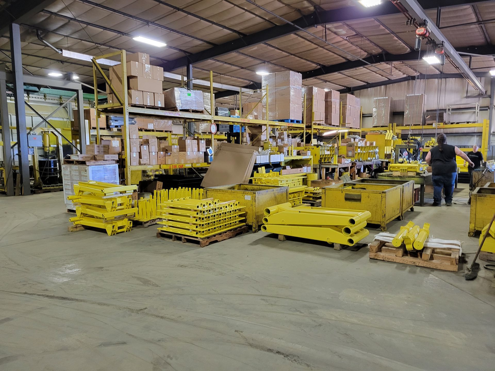A large warehouse filled with lots of yellow pallets and boxes.