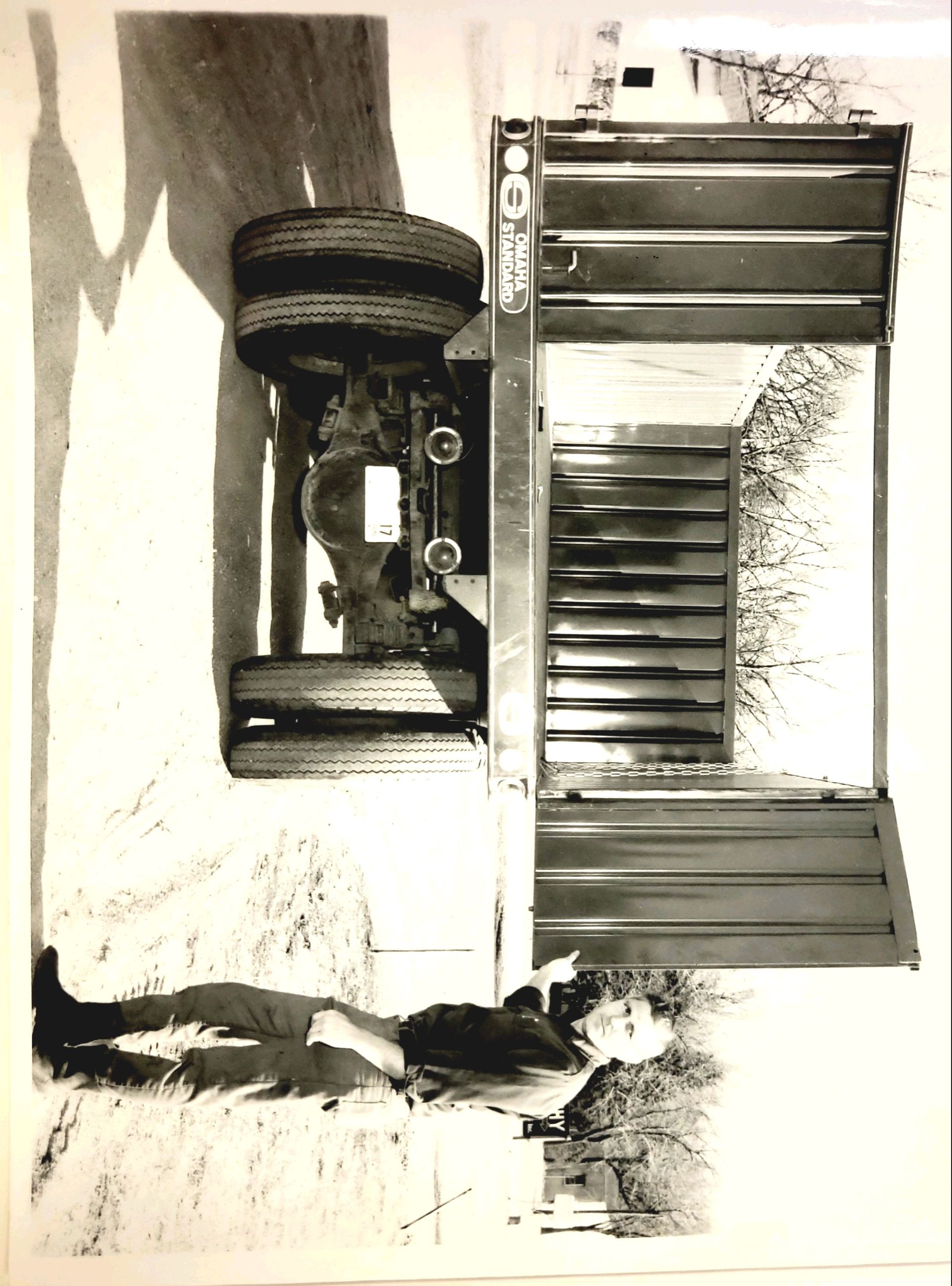 A black and white photo of a man standing next to a truck