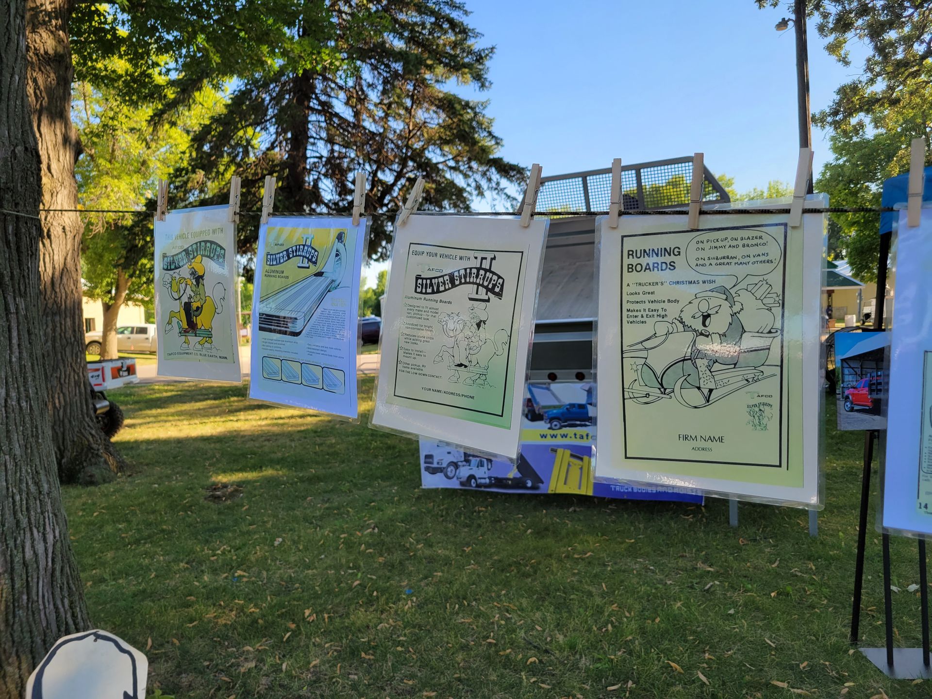 A bunch of posters are hanging on a clothes line in a park