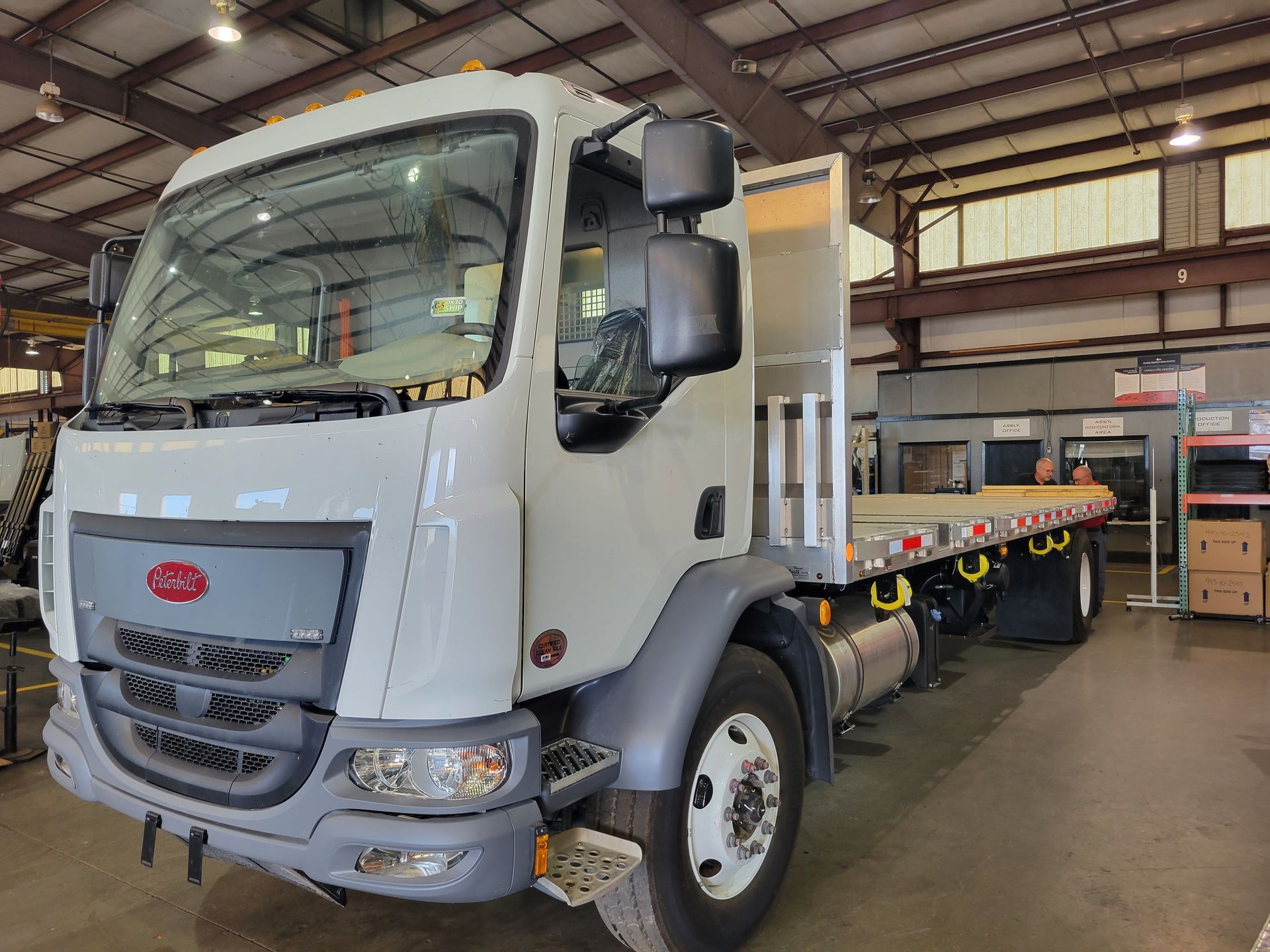 A white flatbed truck is parked in a warehouse.