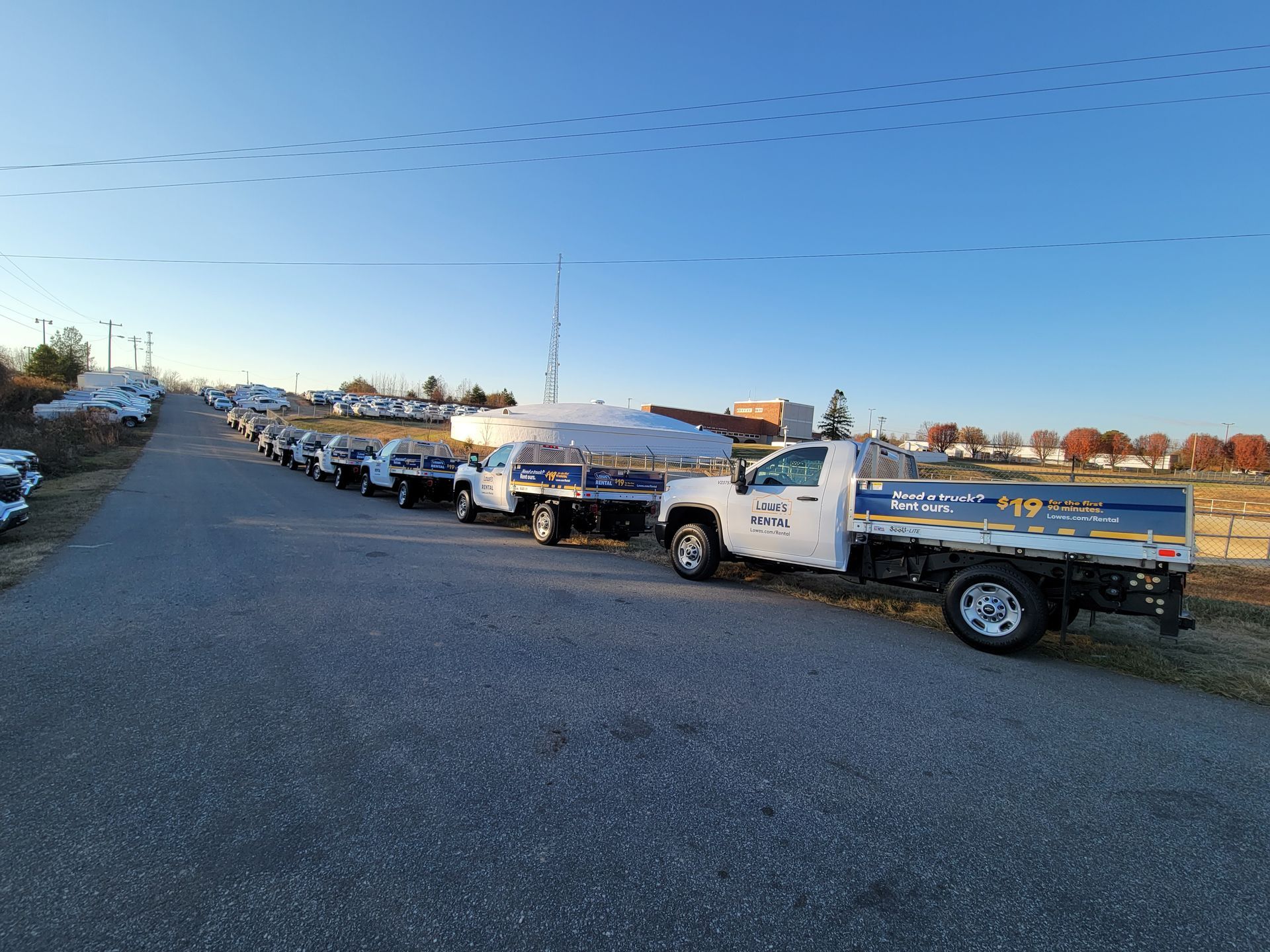 A row of trucks are parked on the side of a road.