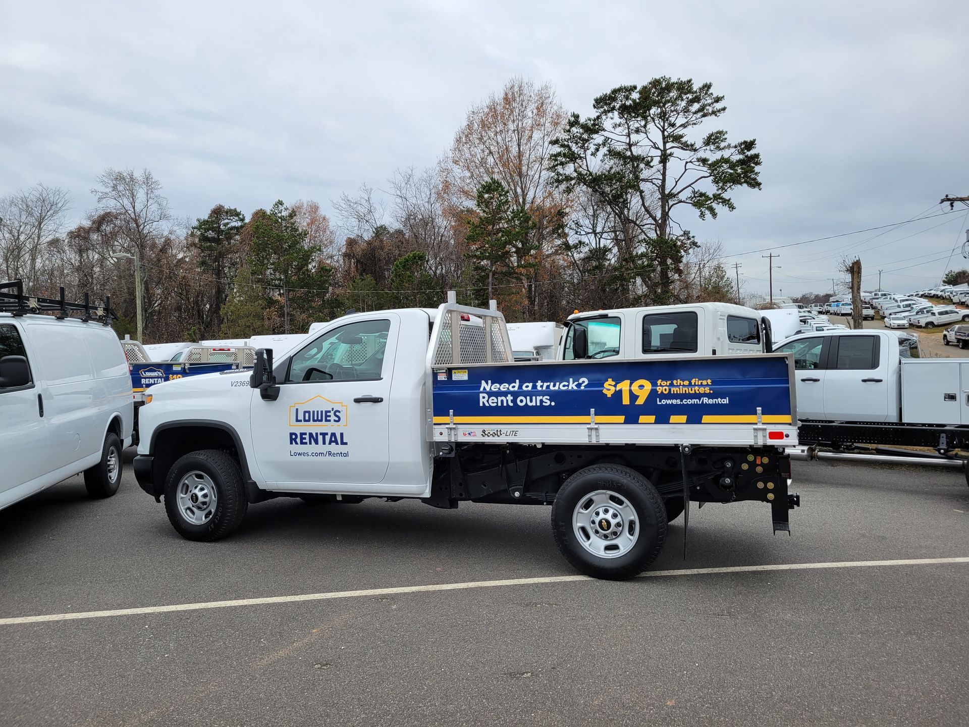 A white truck with a blue bed is parked in a parking lot.