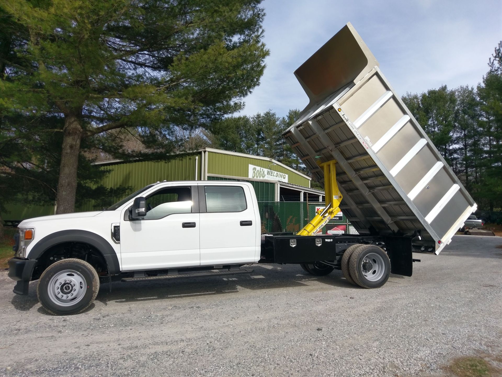 A white dump truck is parked in a gravel lot