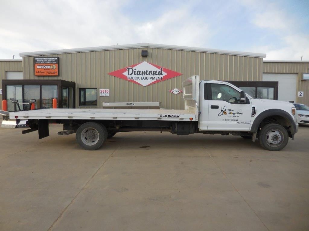 A white tow truck is parked in front of a building.