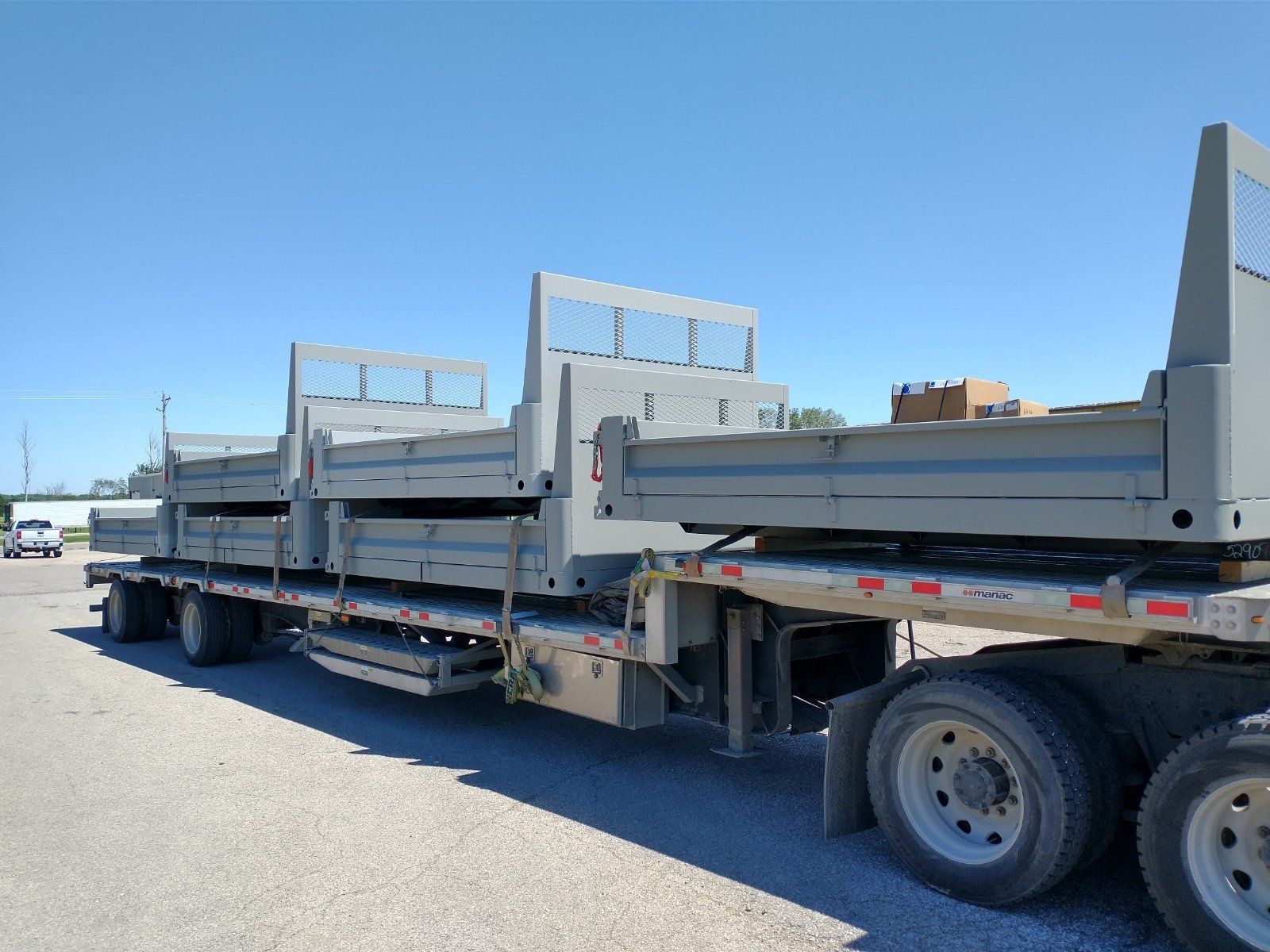 A semi truck with a flatbed trailer is parked on the side of the road.