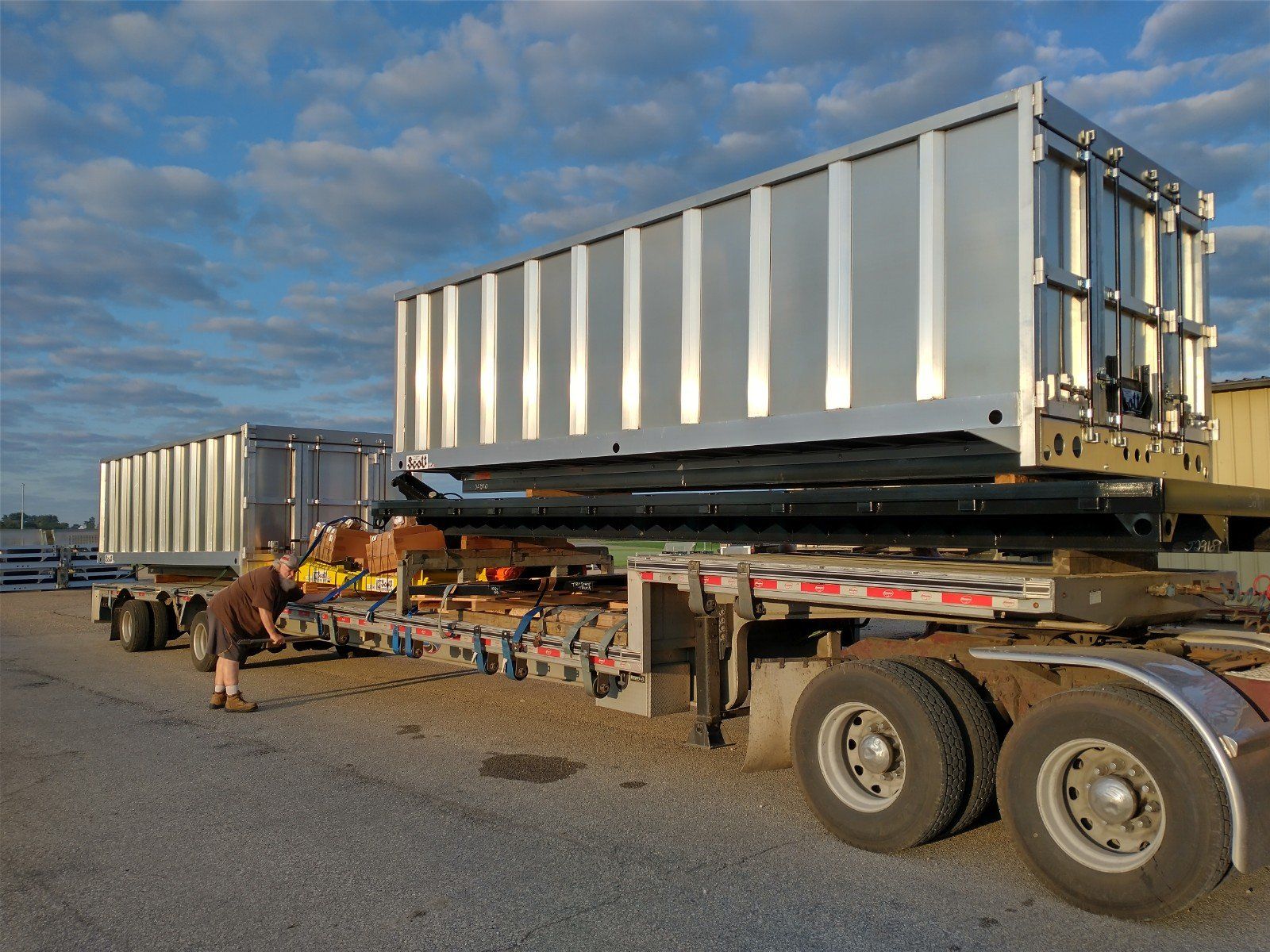 A man standing next to a semi truck with a large container on top of it