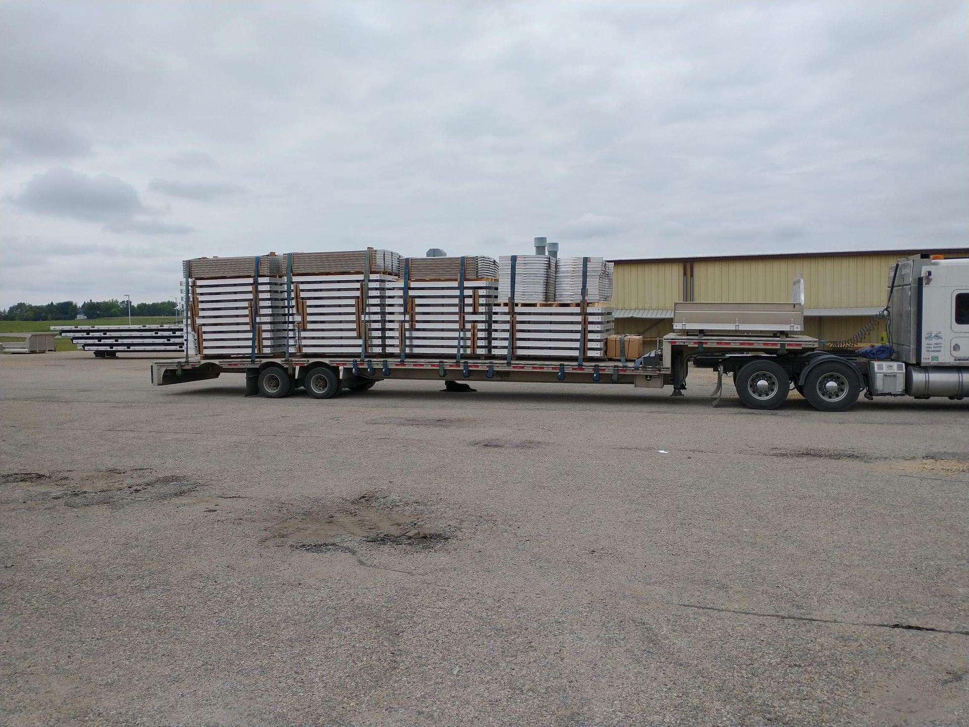 A semi truck is carrying a trailer full of pallets