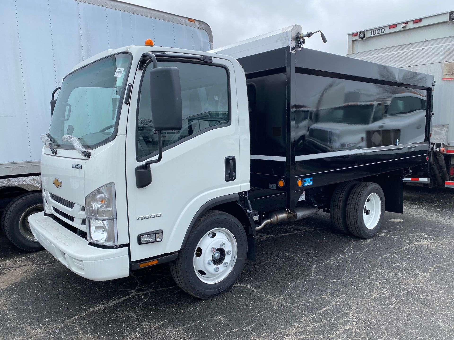 A white truck with a black trailer attached to it is parked in a parking lot.