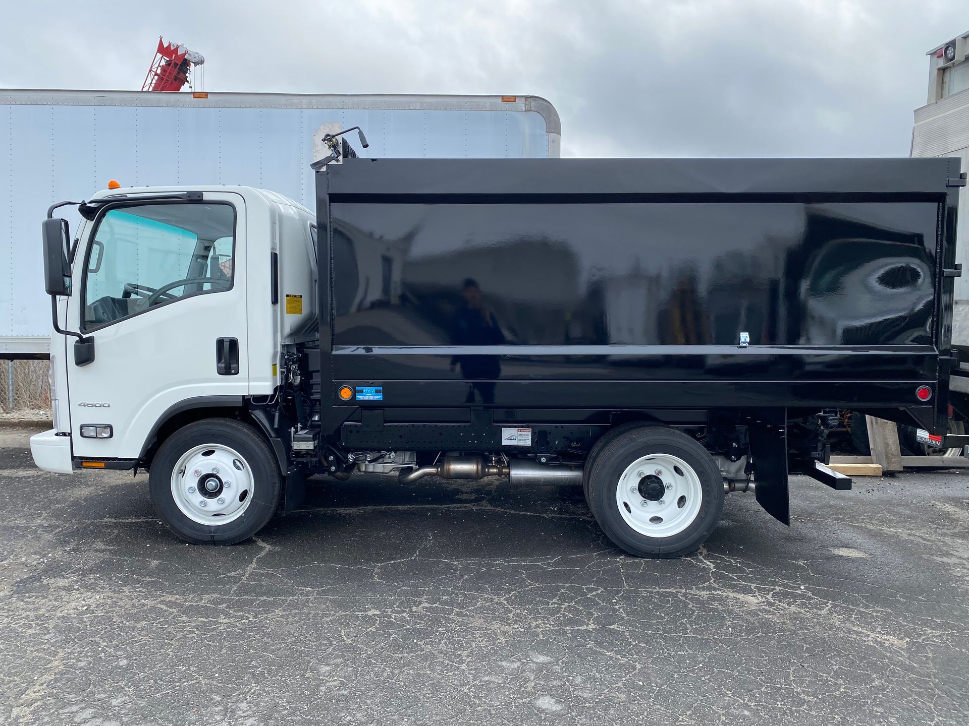 A dump truck is parked in a parking lot next to a white truck.