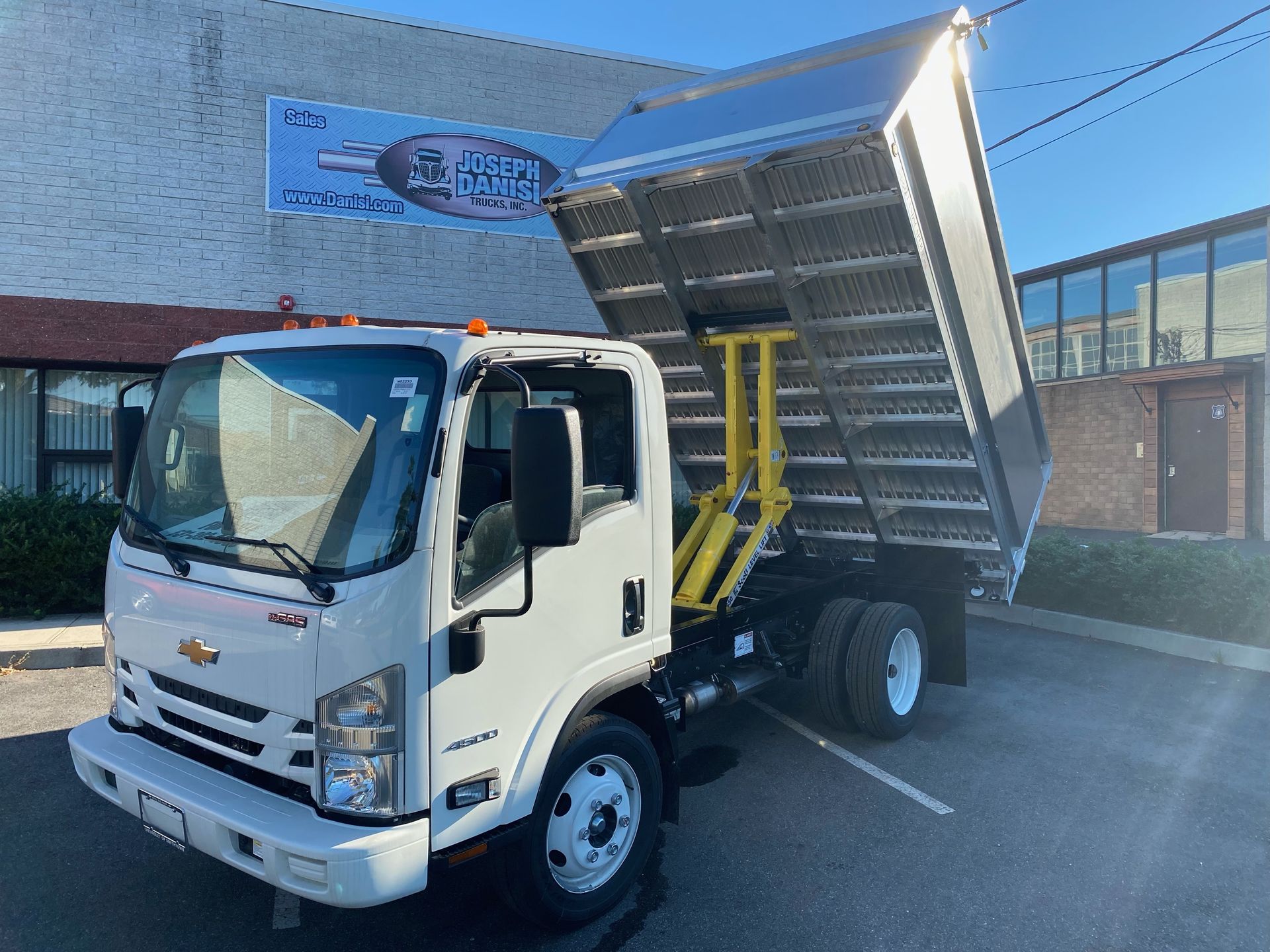 A white dump truck is parked in front of a building.
