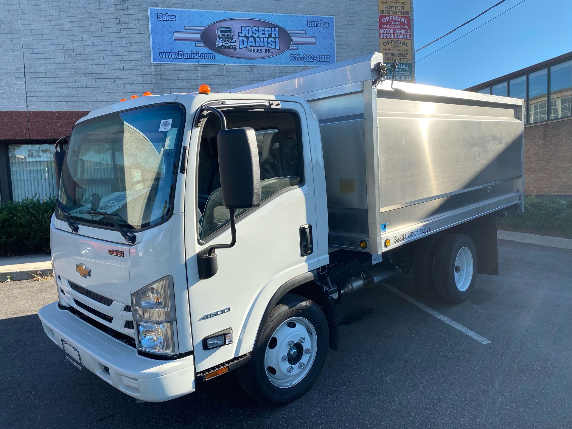 A white dump truck is parked in a parking lot in front of a building.