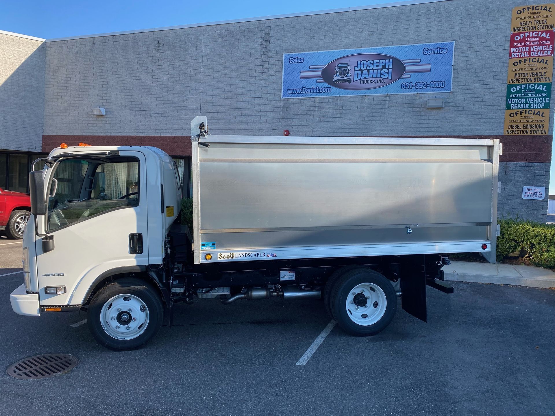 A white dump truck is parked in front of a building.