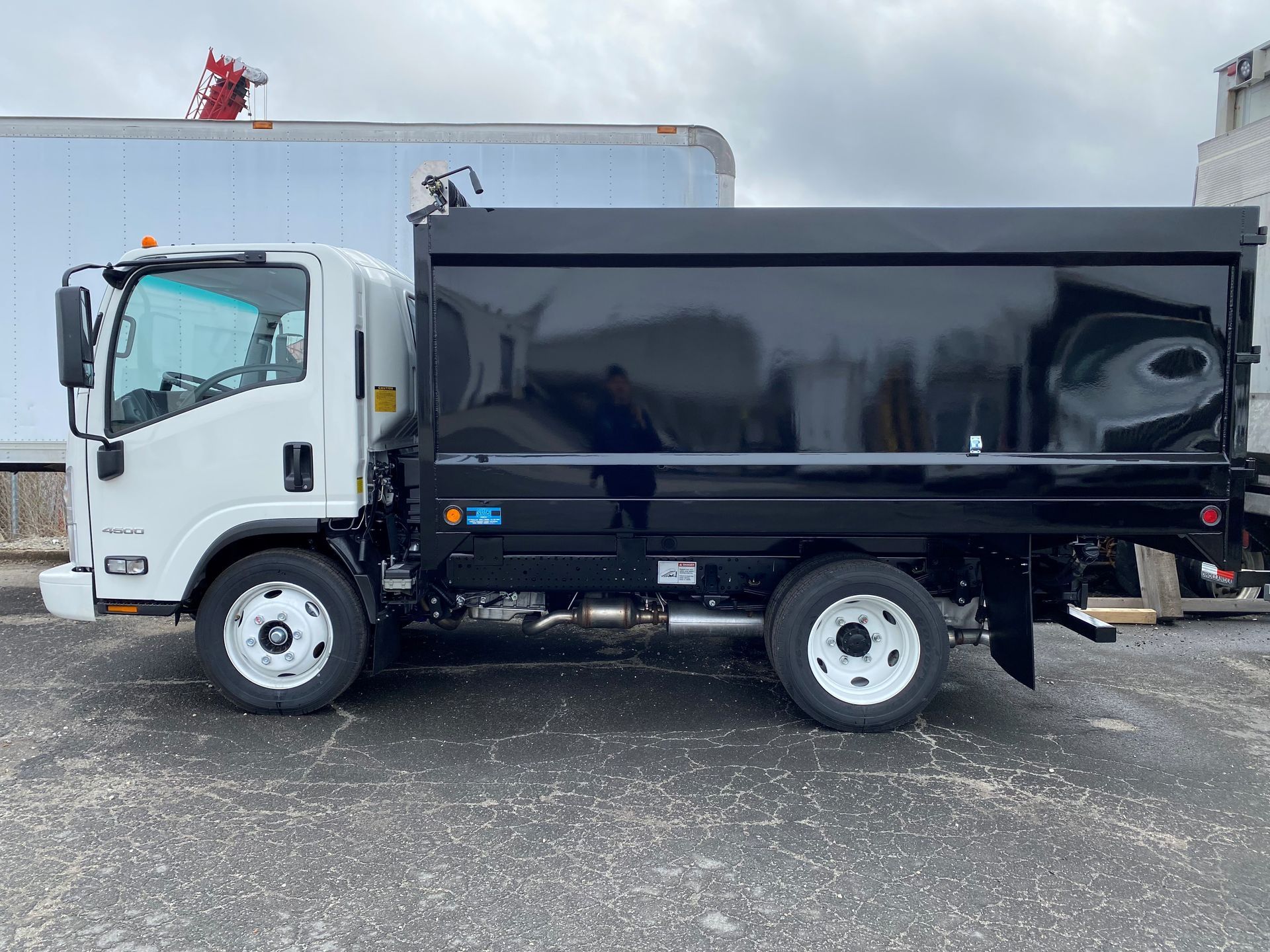 A dump truck is parked in a parking lot next to a white truck.