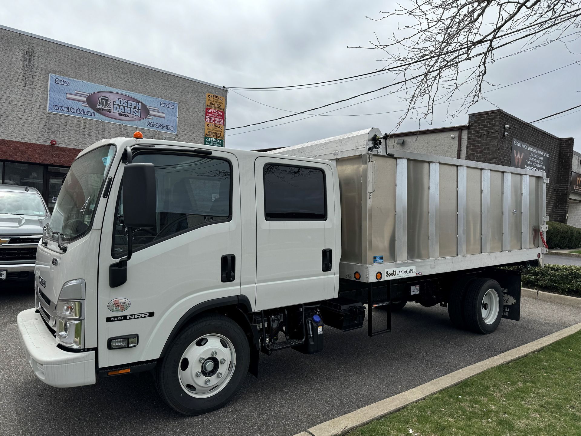 A white dump truck is parked in front of a building.