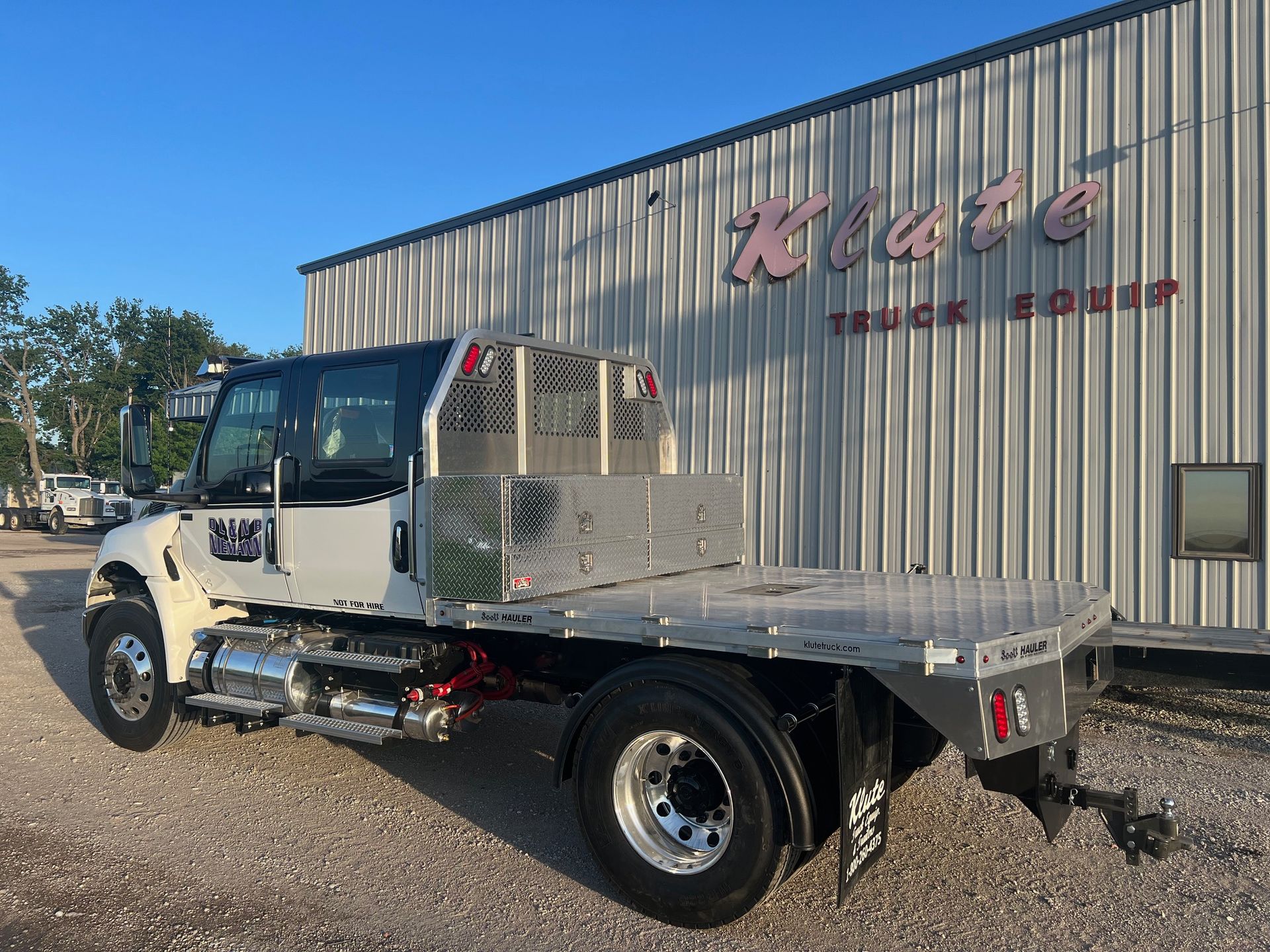 A flatbed truck is parked in front of a building.