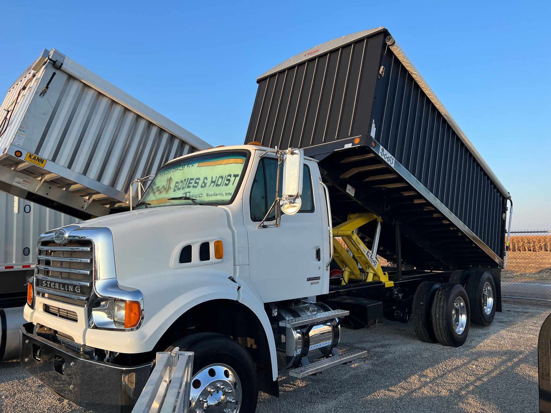 A white dump truck is parked in a gravel lot