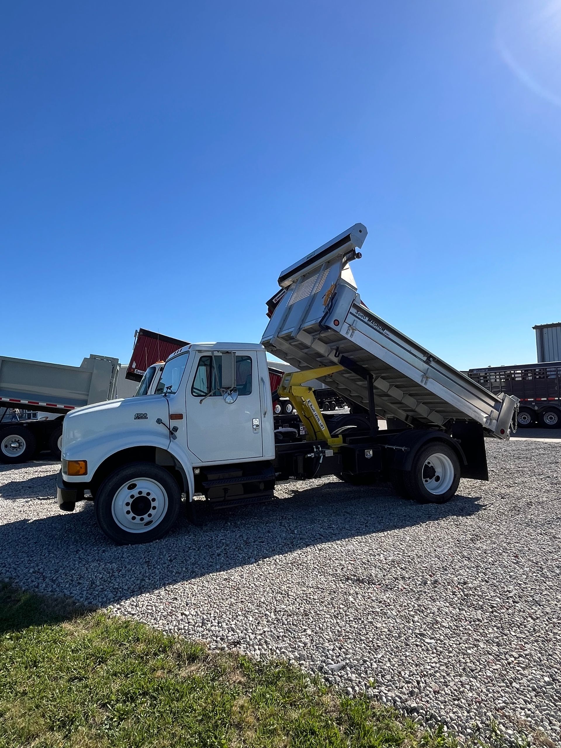 A white dump truck is parked in a gravel lot.