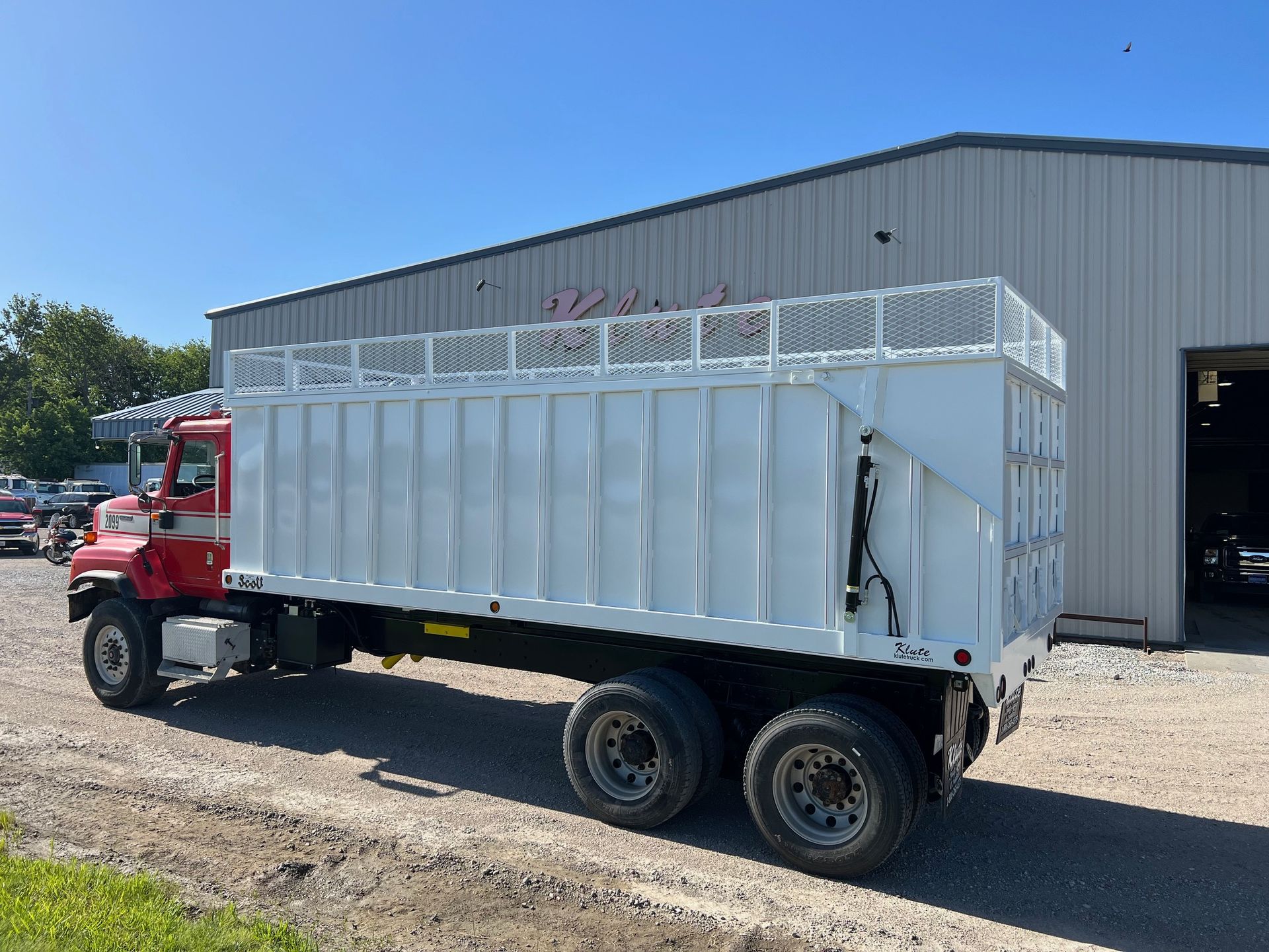 A red and white dump truck is parked in front of a building.