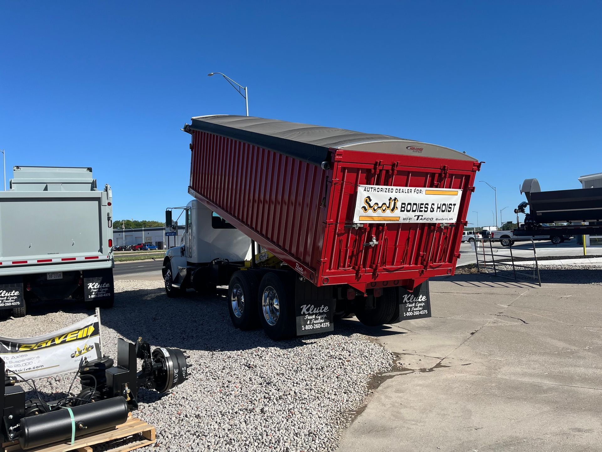 A red dump truck is parked in a gravel lot