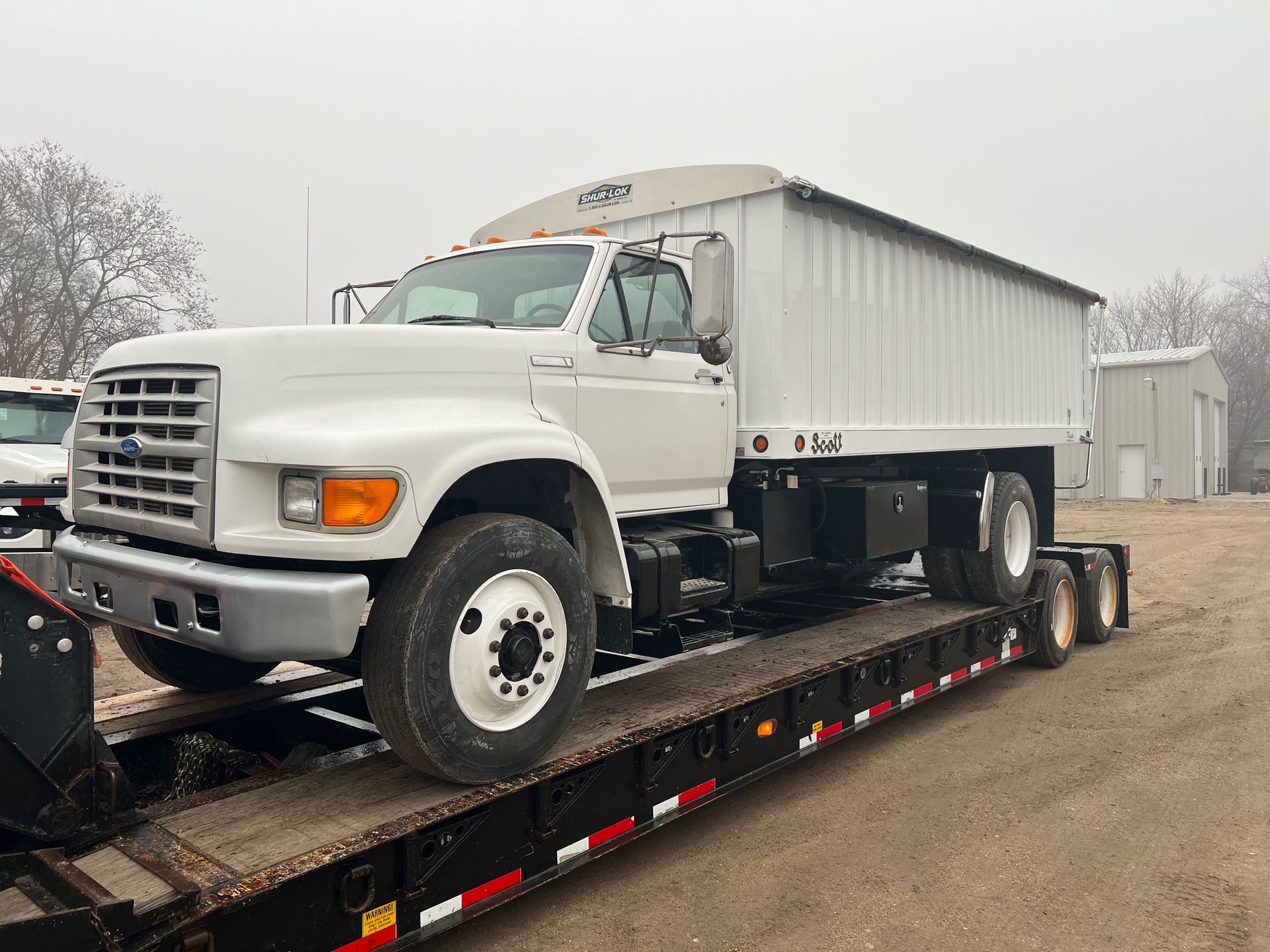 A white truck is sitting on top of a trailer.