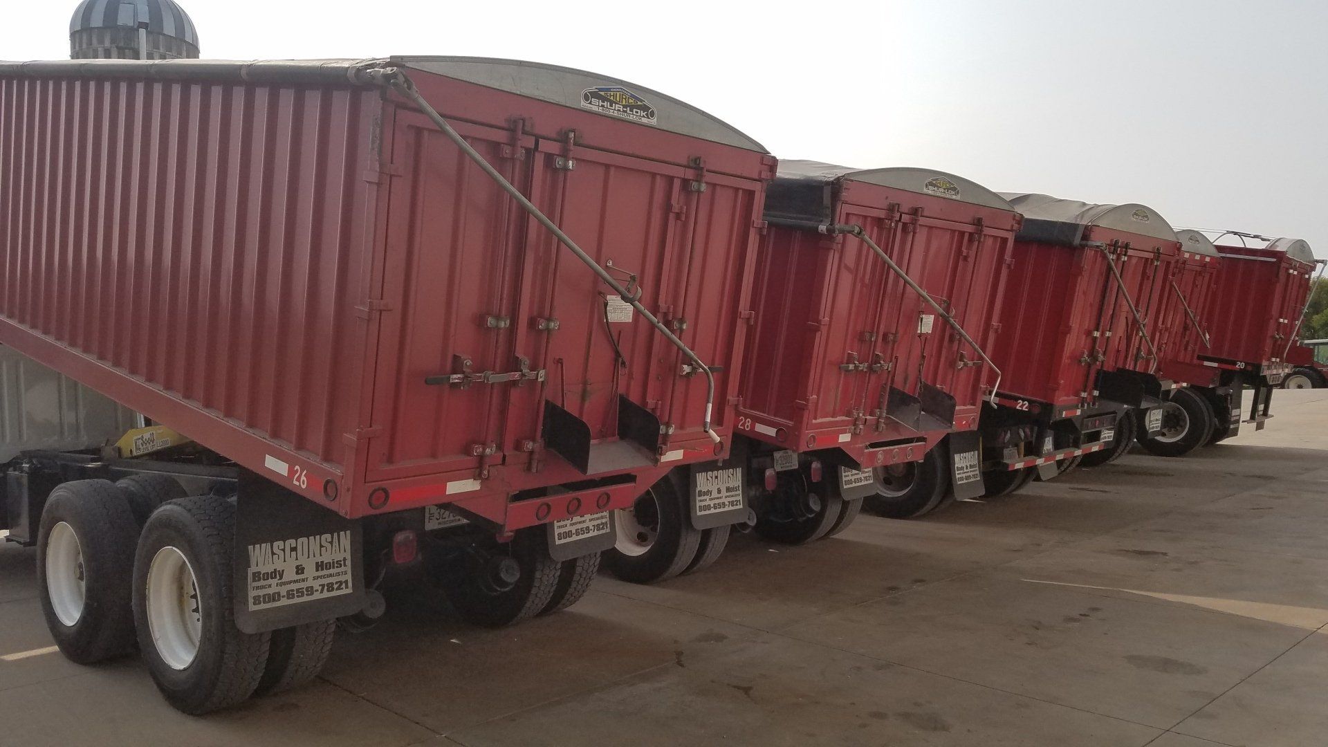 A row of red semi trucks parked next to each other in a parking lot.