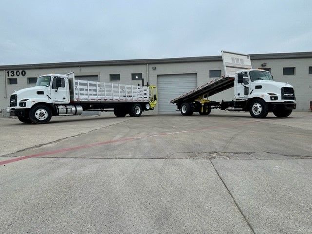 Two white trucks are parked next to each other in front of a building.