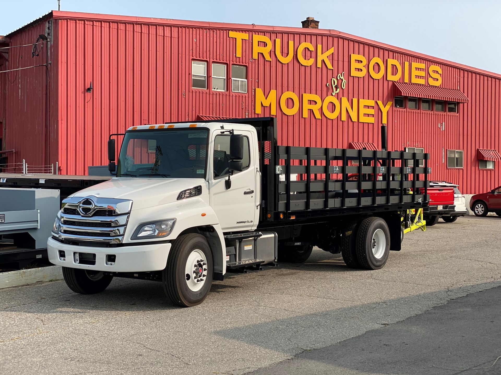 A white truck is parked in front of a red building.