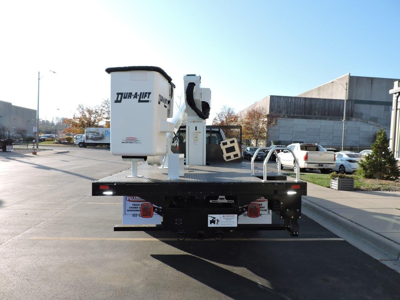 A truck with a bucket on the back is parked in a parking lot