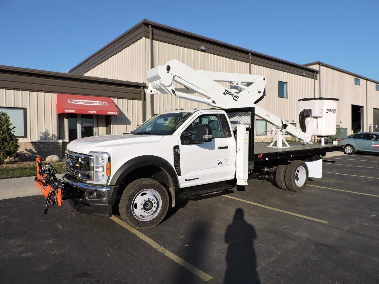A white truck with a crane on top of it is parked in front of a building.