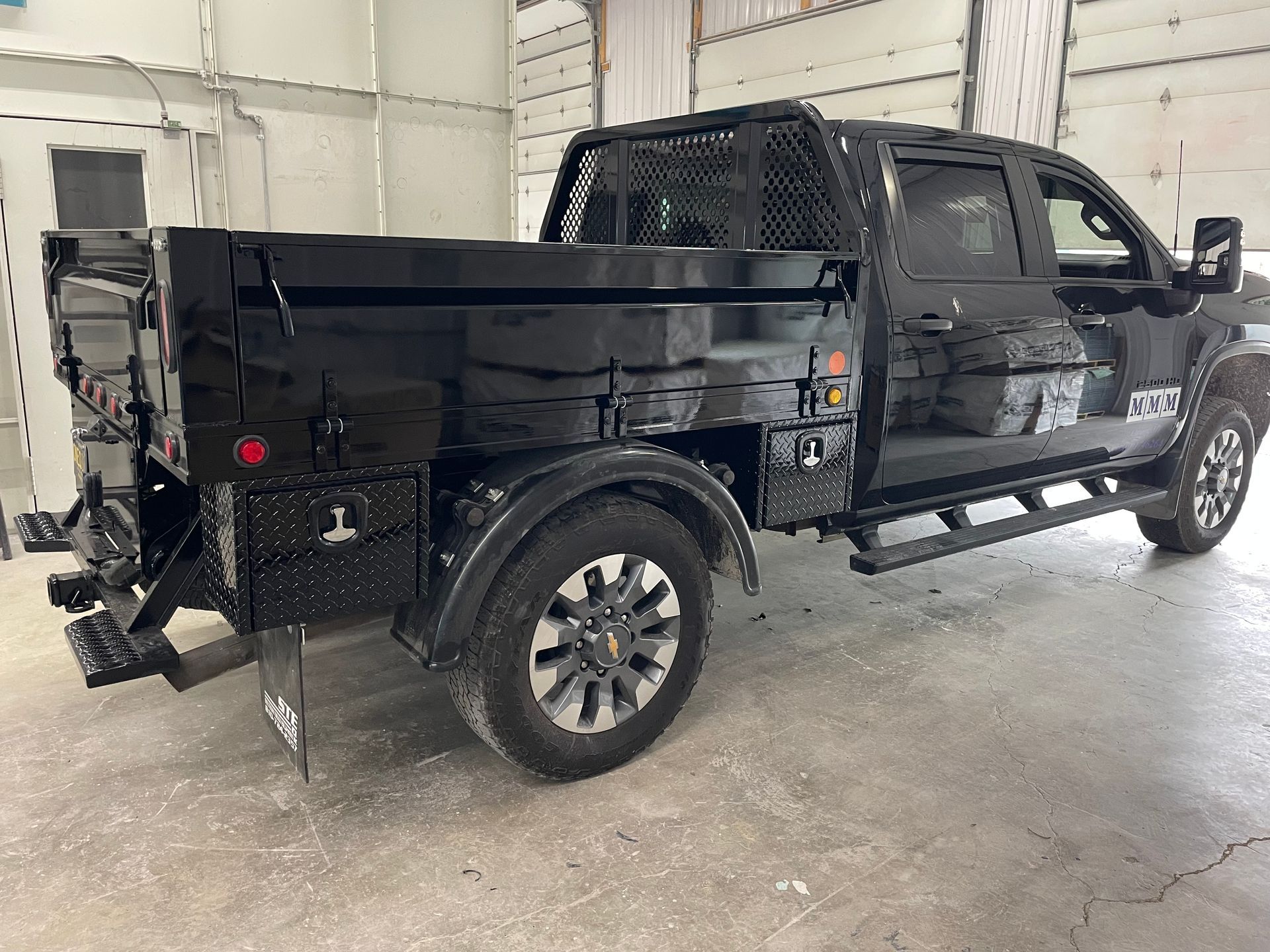 A black truck with a dump bed is parked in a garage.