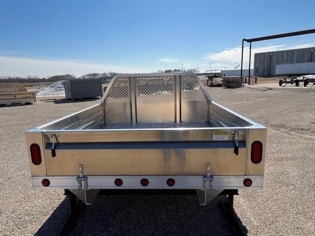 A stainless steel trailer is parked in a gravel lot