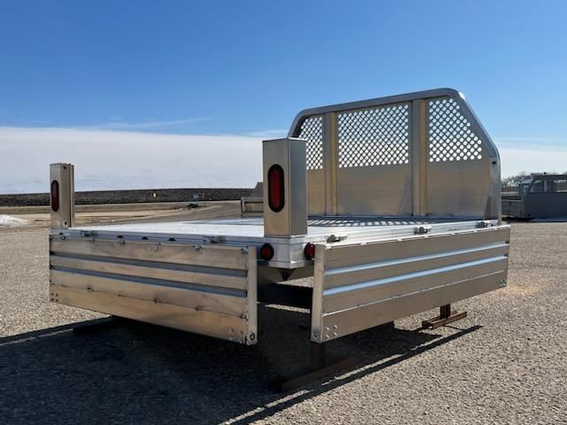 An aluminum truck bed is sitting on a gravel road.