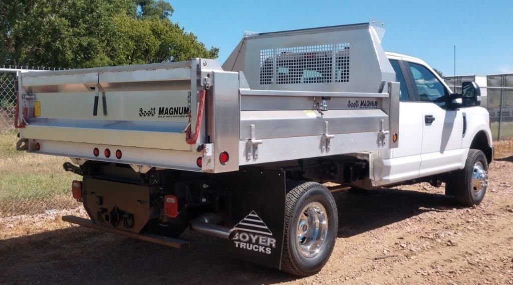 A white dump truck is parked on a dirt road.