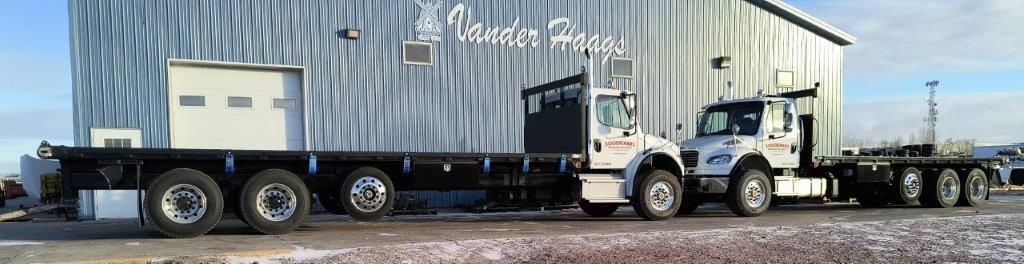 A large semi truck is parked in front of a building.