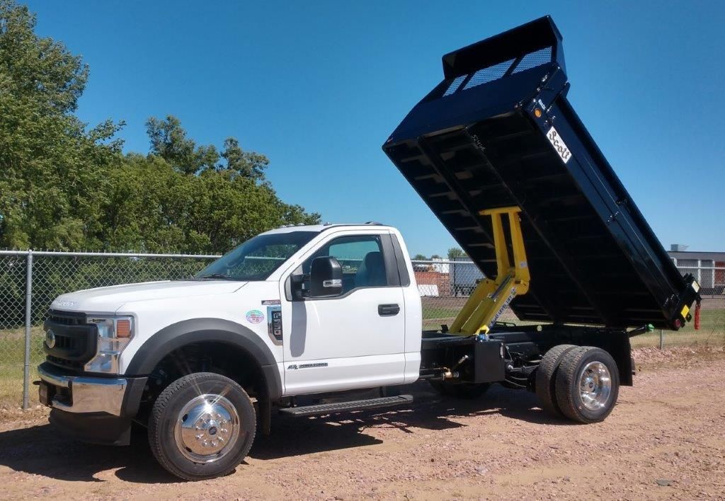 A white dump truck is parked in a dirt lot