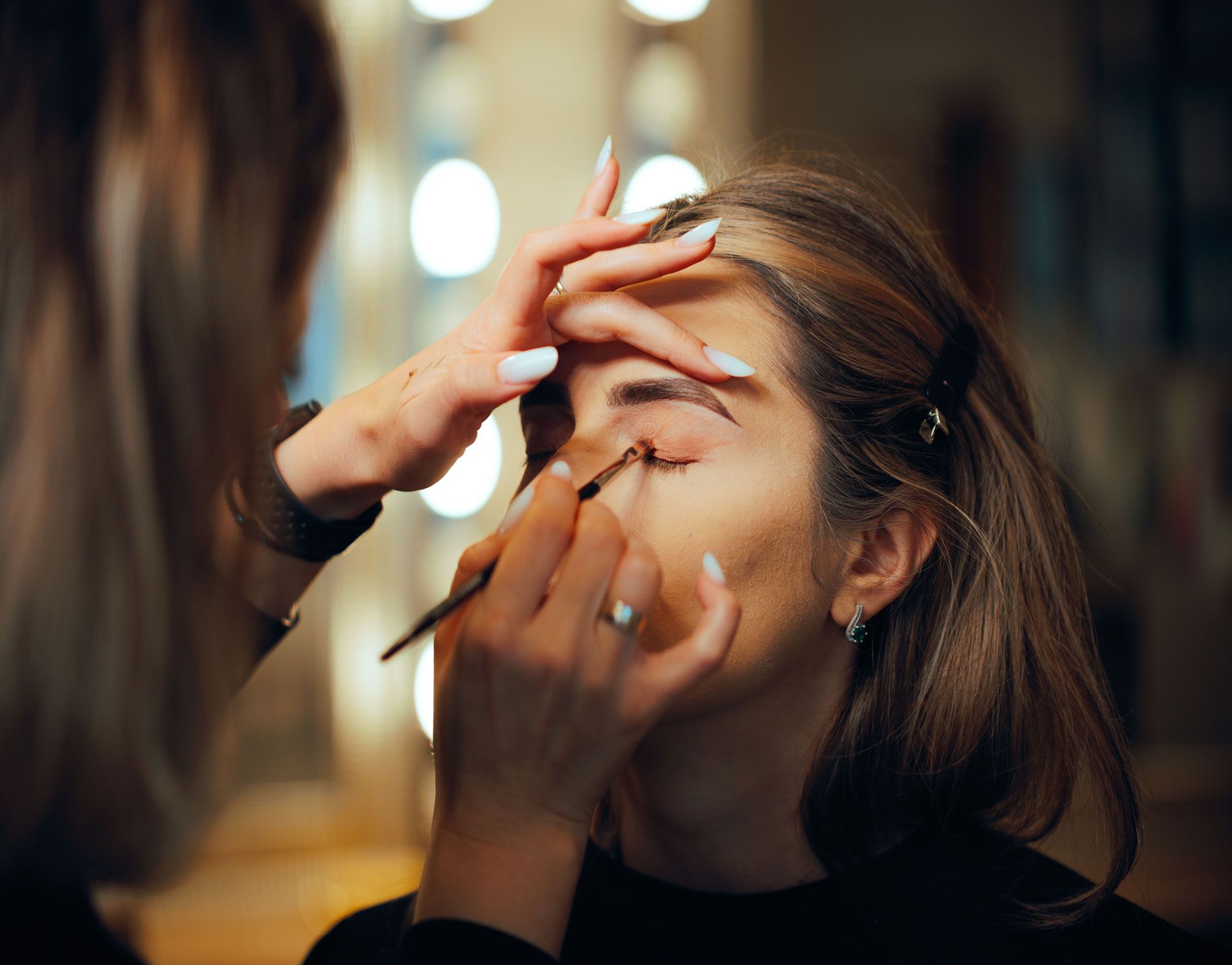 Makeup artist applying eyeliner to a person's eye with a brush, indoors.