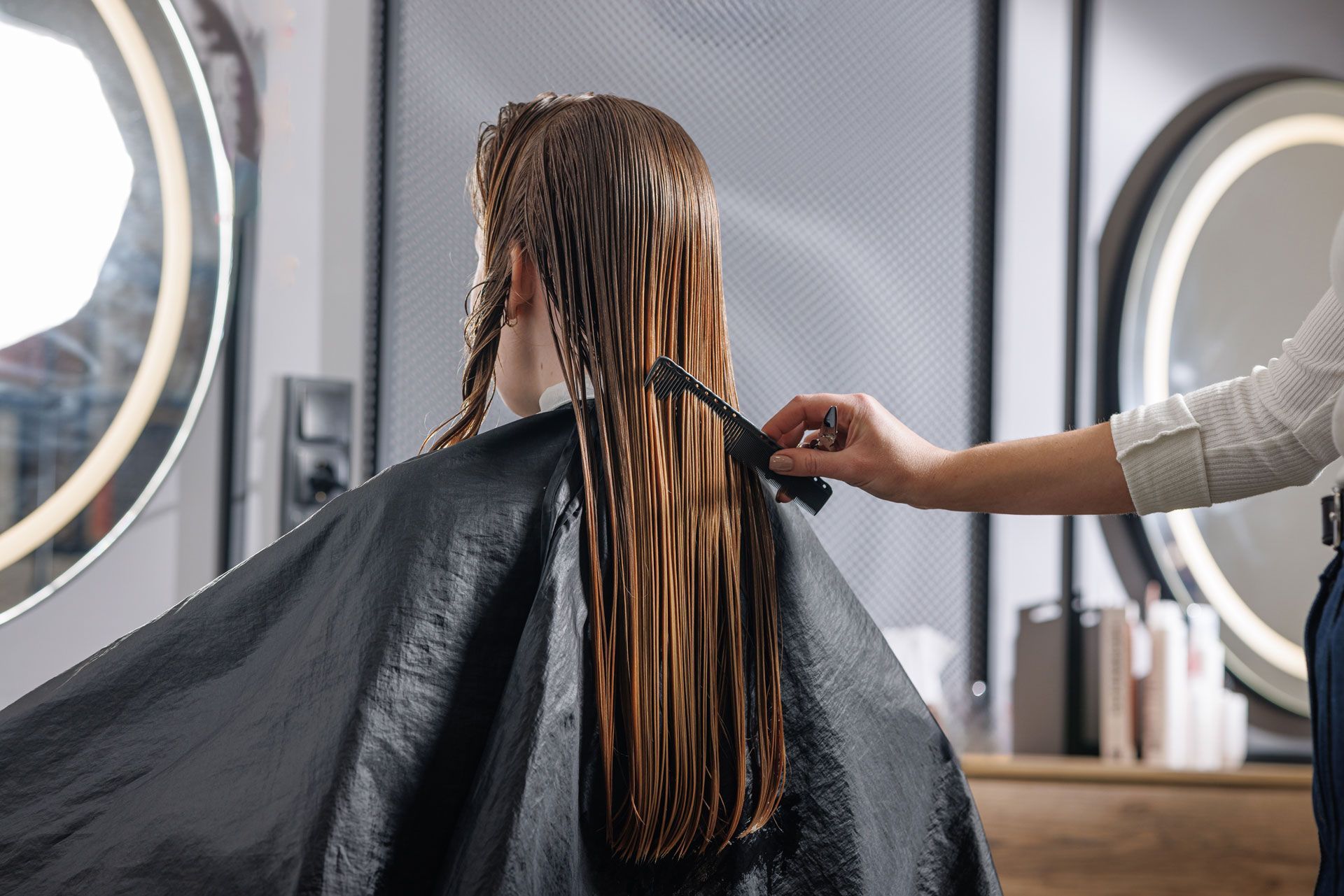 Hairdresser combing wet hair in a salon, preparing for a haircut.