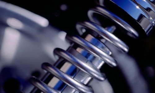 Primer plano de un muelle helicoidal de metal brillante sobre un fondo azul oscuro.