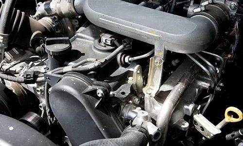 Primer plano del compartimento del motor de un coche con mangueras, piezas metálicas
