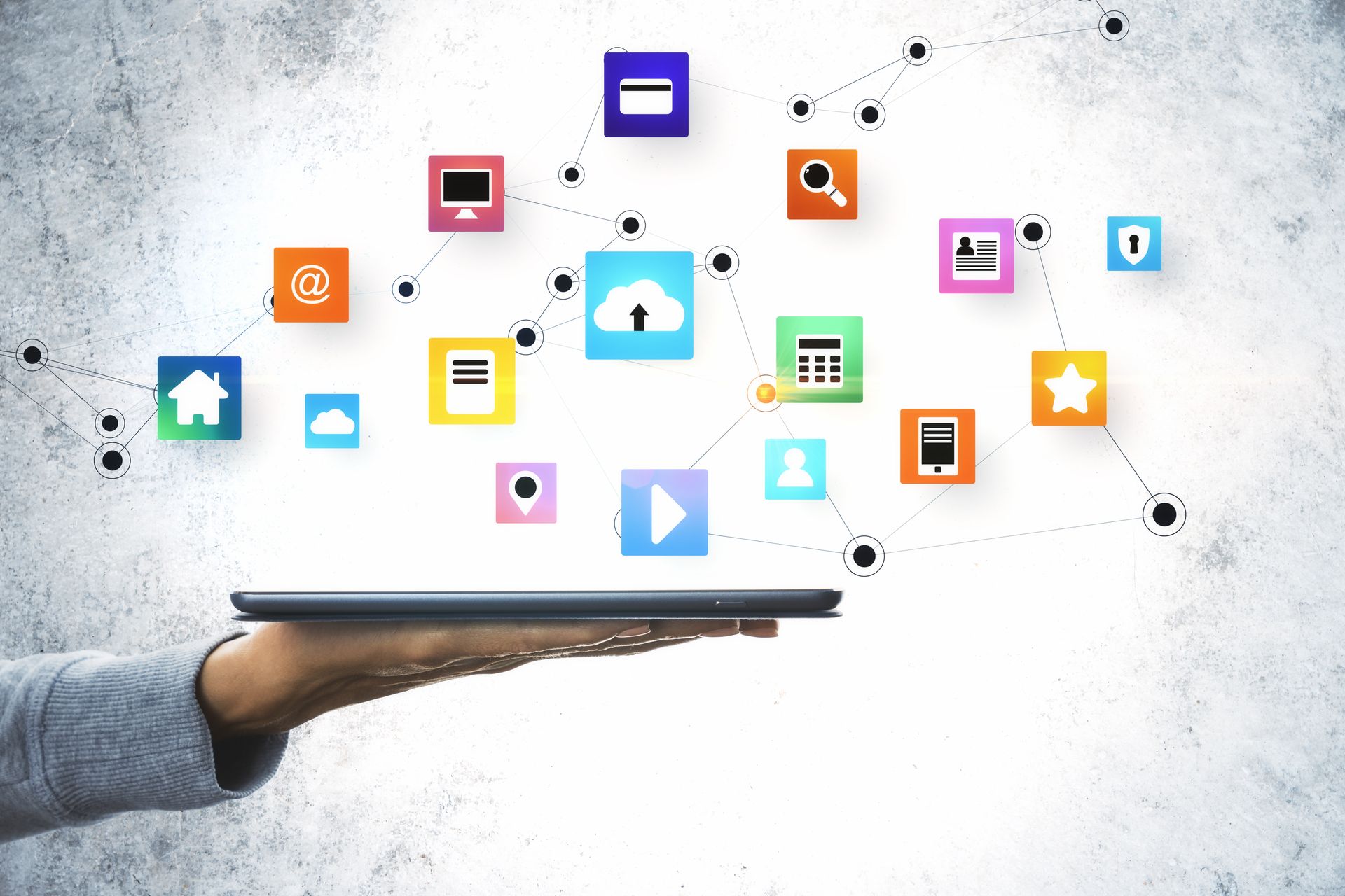 Hand holding a tablet with colorful app icons floating above it on a white background