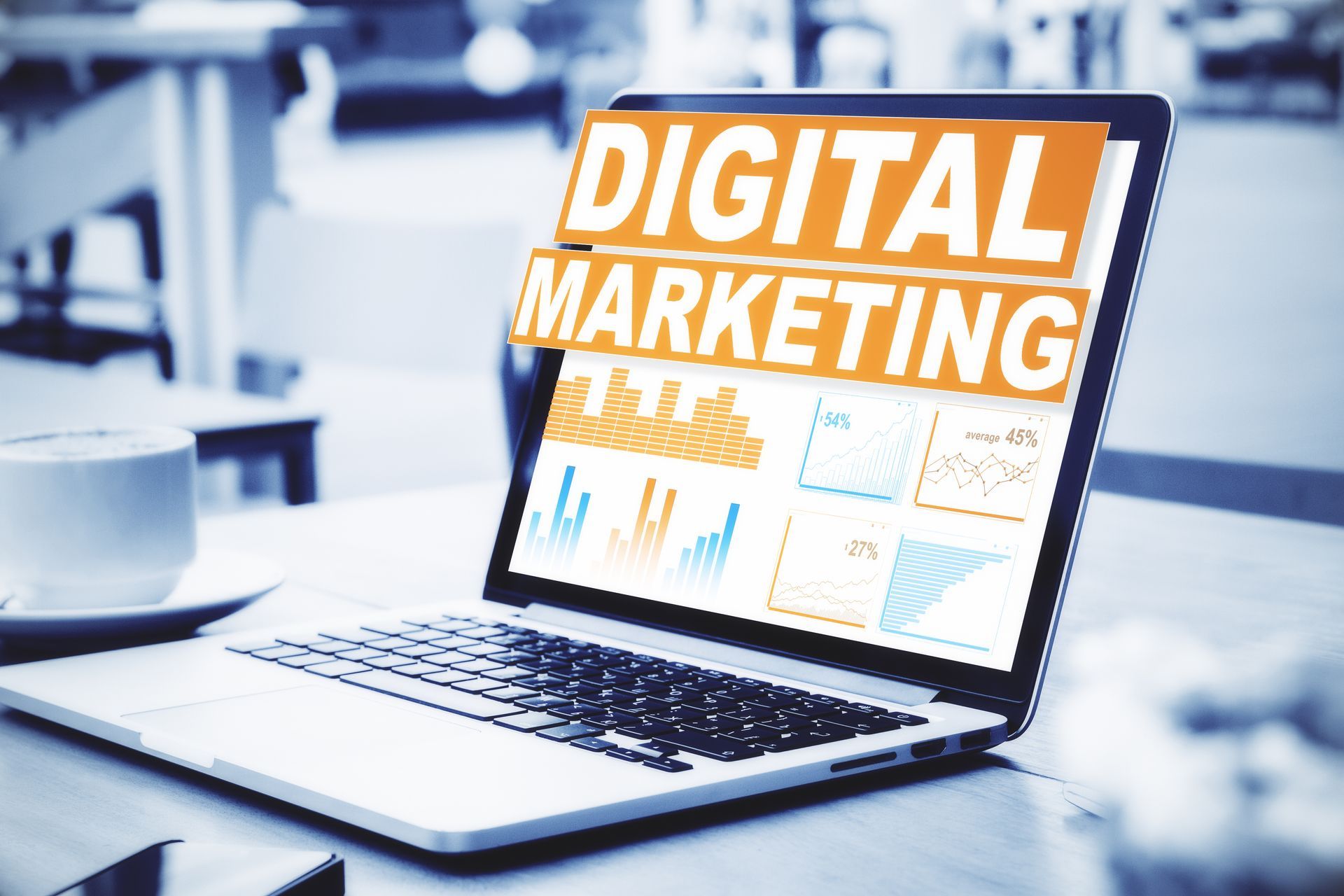 Laptop on desk displaying a digital marketing dashboard in orange and white.