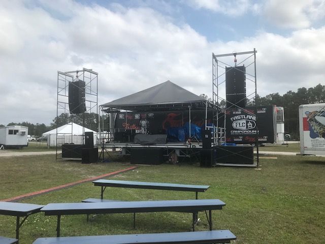A stage is being set up in the middle of a grassy field.