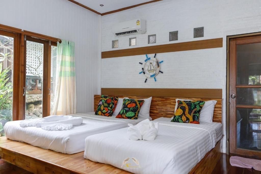 Bedroom with two beds, white bedding, wooden headboard and base, decorated with colorful pillows.