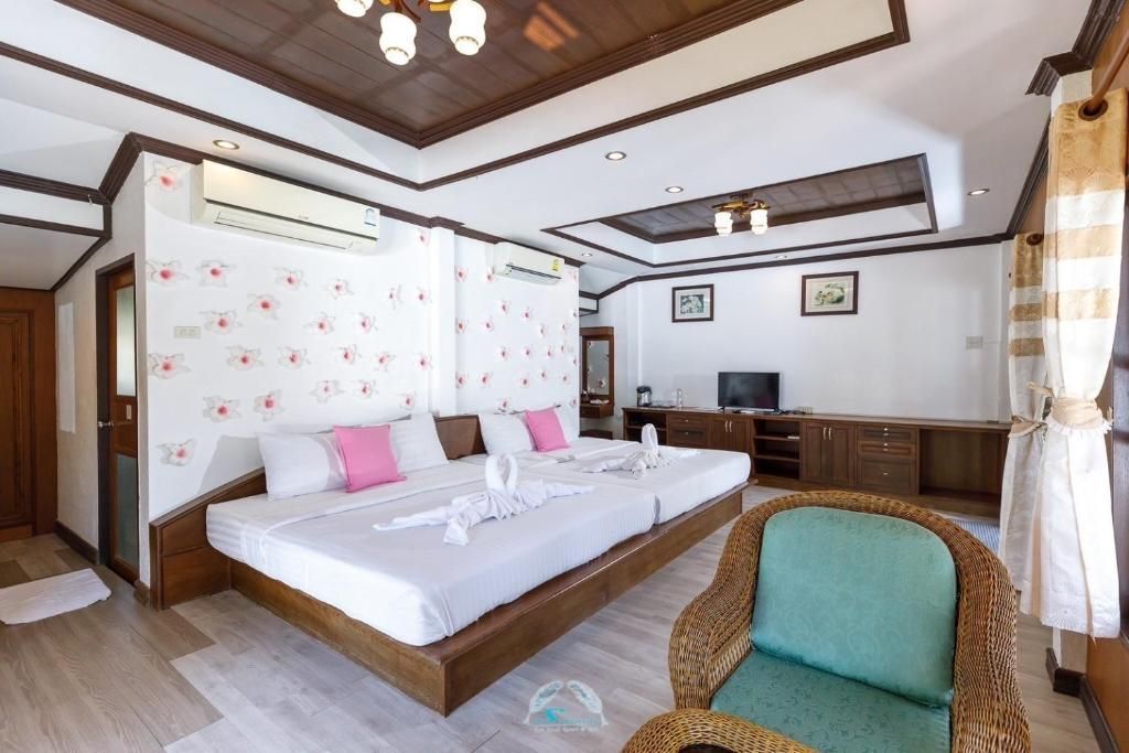 Bedroom with two beds, floral wallpaper, wicker chair, wooden furniture, and air conditioning.