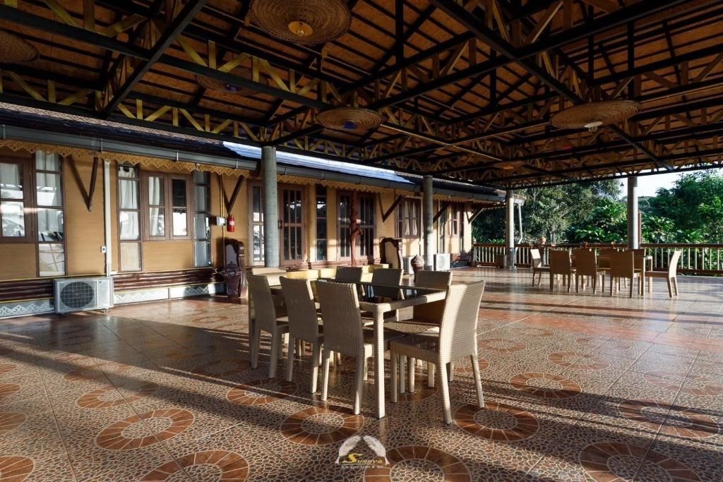 Covered outdoor dining area with tables and chairs, building in the background.