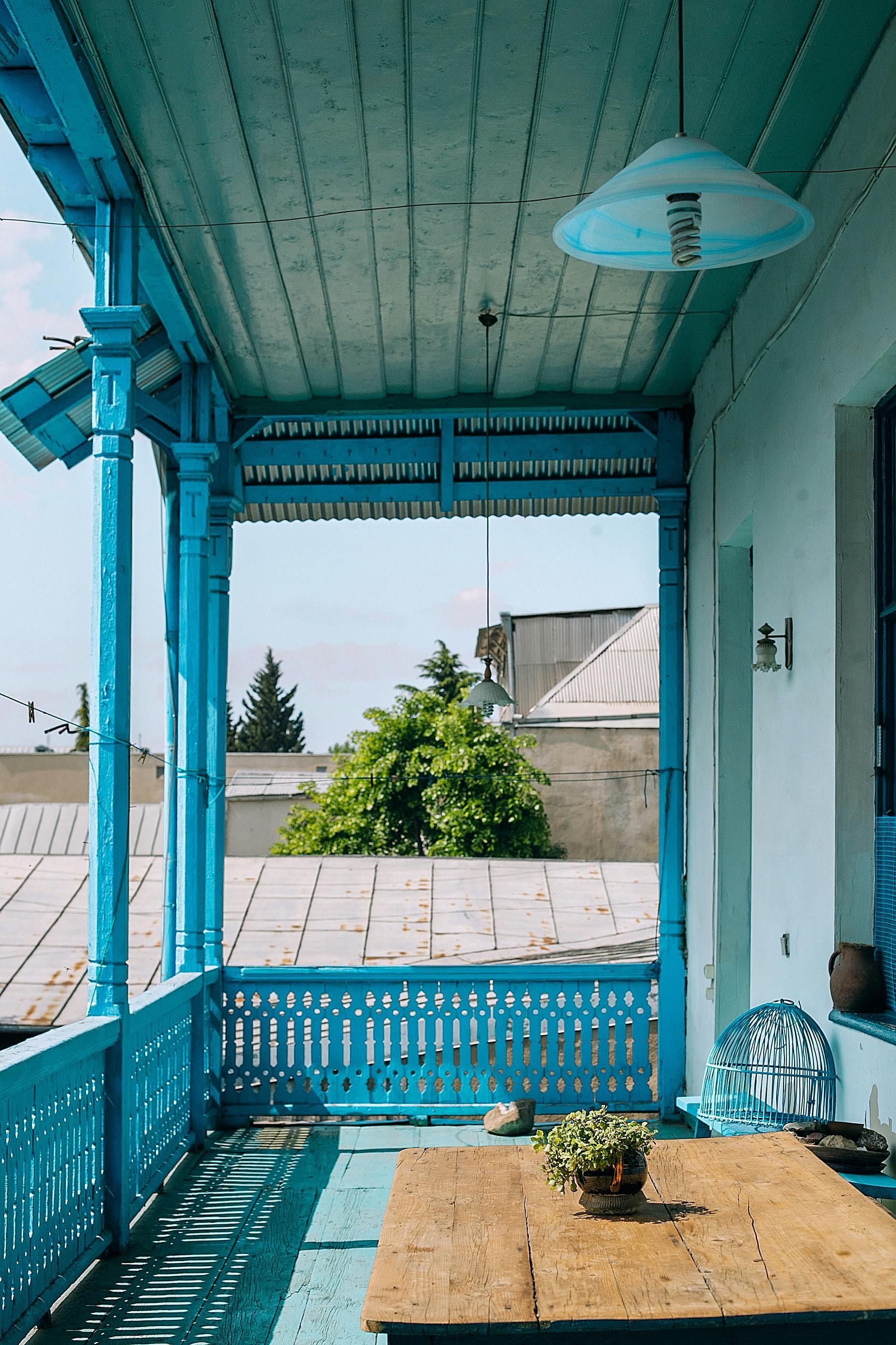 A blue porch with a wooden table and chairs