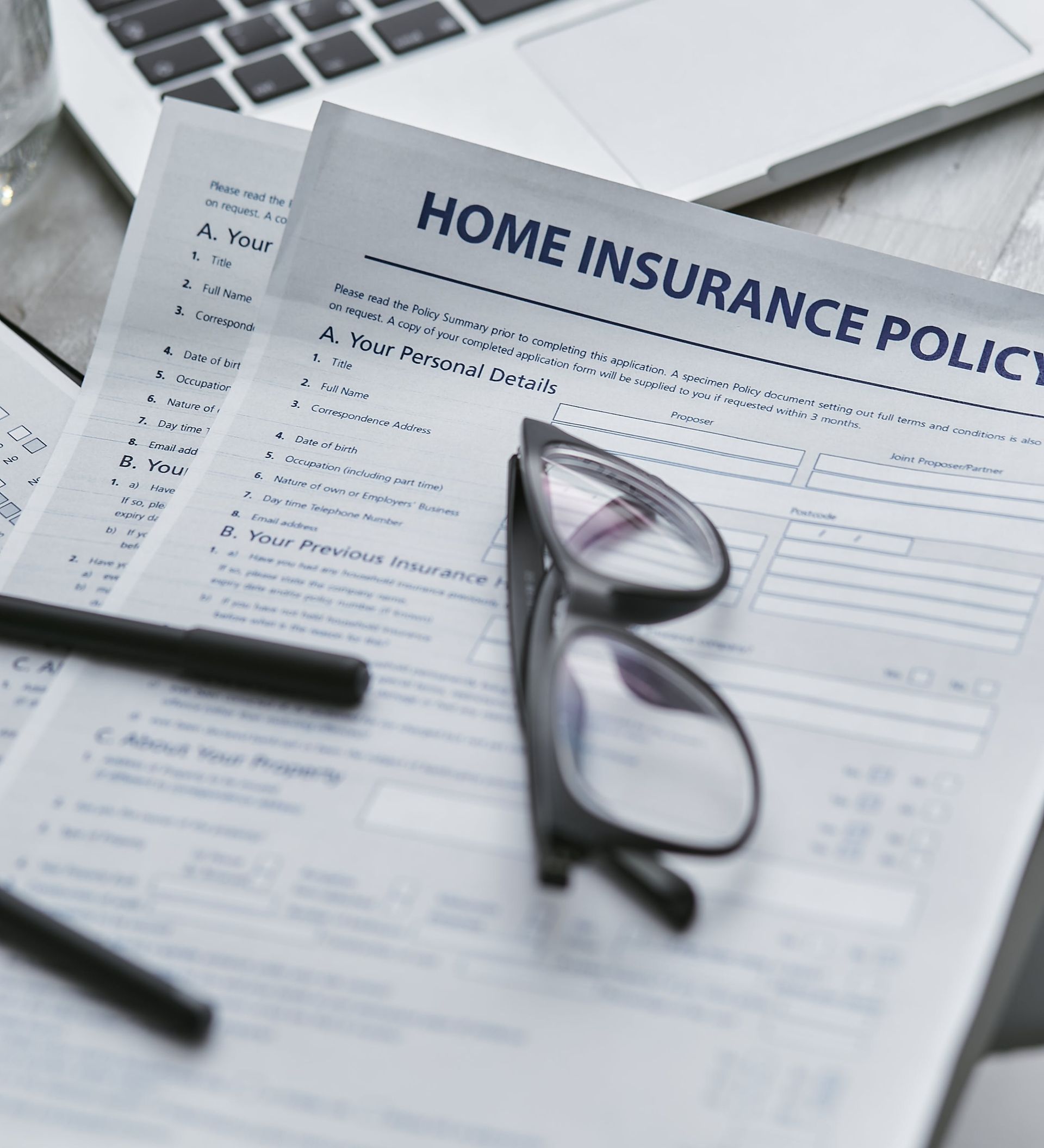 A pair of glasses sit on top of a home insurance policy
