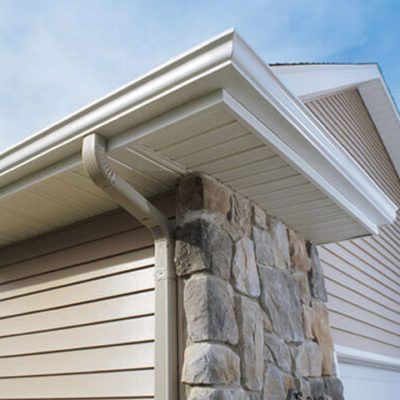 A house with a stone wall and a gutter on the side of it.