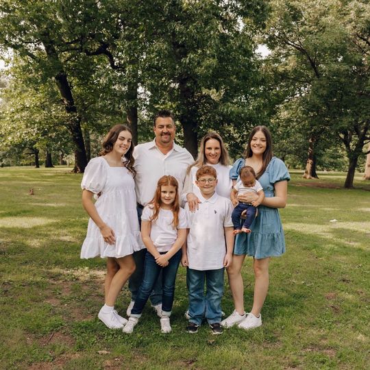 A family is posing for a picture in a park.