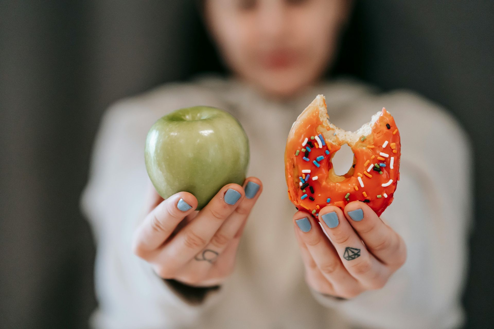 woman holding apple and donut